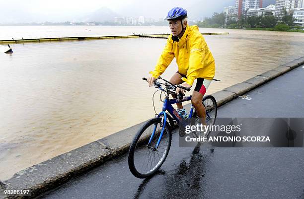 Ciclist rides along the Rodrigo de Freitas lagoon , whose water has been turned brown by the current storm affecting Rio de Janeiro, on April 6,...