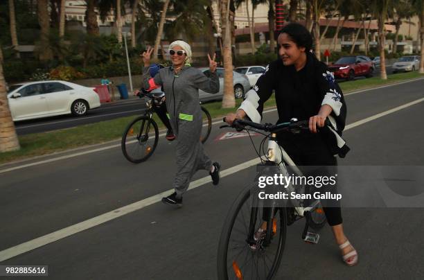 Young woman wearing an abaya designed specifically for sports runs along side two girls on bicycles on the Corniche seafront on June 24, 2018 in...