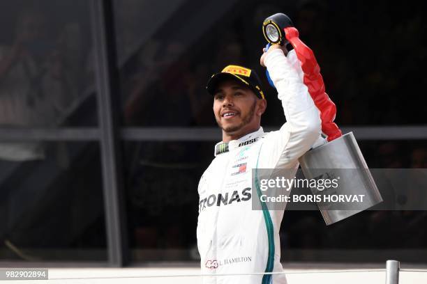 Winner Mercedes' British driver Lewis Hamilton holds his trophy as he celebrates on the podium after the Formula One Grand Prix de France at the...