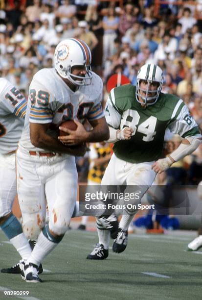 S: Running back Larry Csonka of the Miami Dolphins in action carries the ball chased by defensive end Mark Lomas of the New York Jets circa mid...