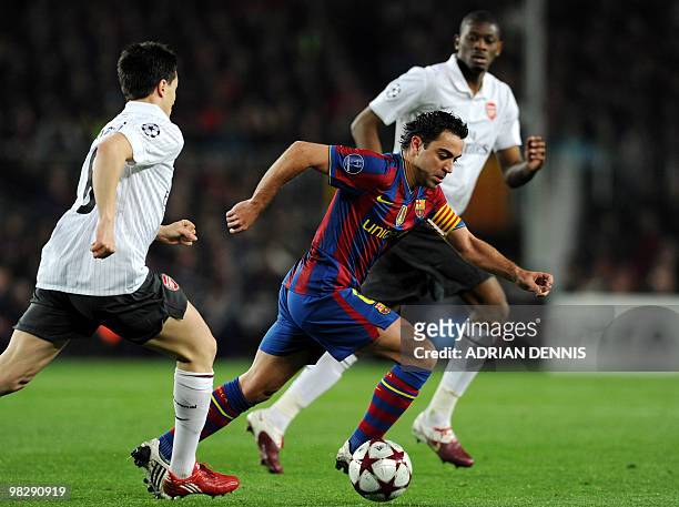 Barcelona's midfielder Xavi Hernandez runs with the ball away from Arsenal's French midfielder Samir Nasri and Abou Diaby during the Champions League...
