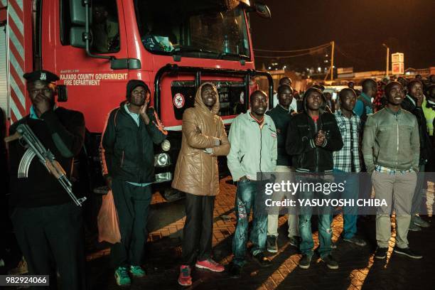 People in Kenya watch the Russia 2018 World Cup Group H football match between Japan and Senegal on a giant display near a sports betting company in...