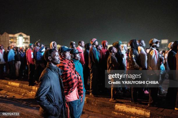 People in Kenya watch the Russia 2018 World Cup Group H football match between Japan and Senegal on a giant display near a sports betting company in...