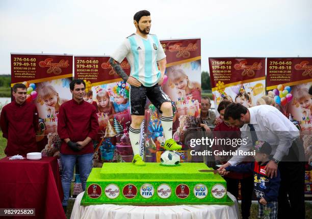 Fans cut a cake during a celebration made by fans and local villagers of Bronnitsy who gather to commemorate Lionel Messi's 31st birthday at a park...