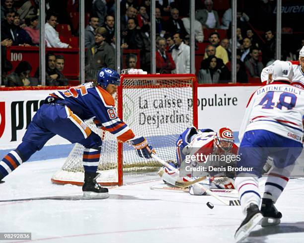 Petr Klima of the Edmonton Oilers skates against Jean-Jacques Daigneault and goaltender Patrick Roy of the Montreal Canadiens in the early 1990's at...