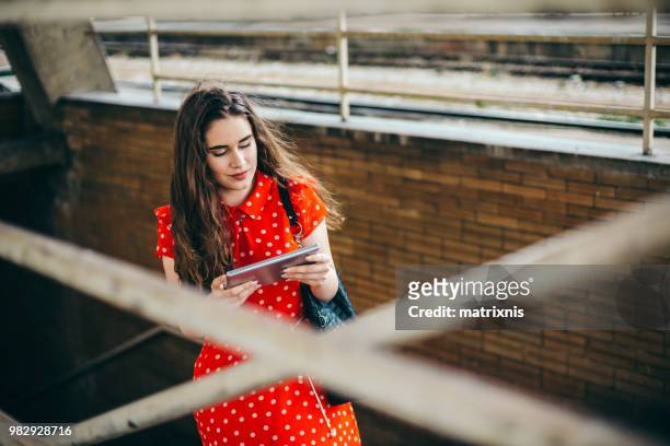 voyageur femme dans une robe rouge se trouve sur la gare ferroviaire - matrixnis photos et images de collection