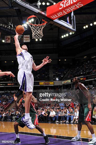 Spencer Hawes of the Sacramento Kings dunks against John Salmons of the Milwaukee Bucks during the game at Arco Arena on March 19, 2010 in...