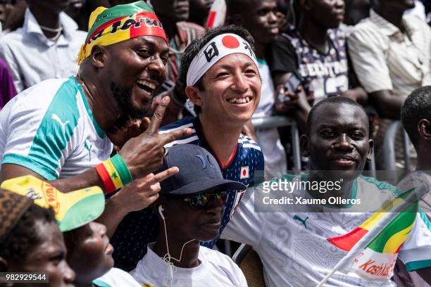Senegal fans poses with a Japan fan as they watch game two of group H of the World Cup match between Japan and Senegal at Obelisque square on June...