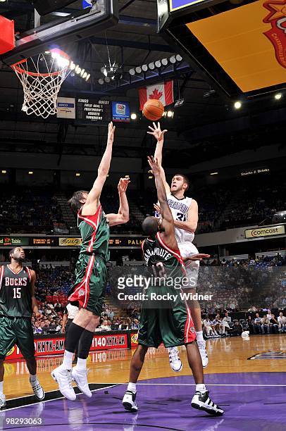 Spencer Hawes of the Sacramento Kings shoots over Andrew Bogut and Luc Mbah a Moute of the Milwaukee Bucks during the game at Arco Arena on March 19,...