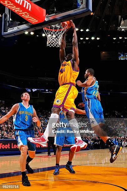 Anthony Tolliver of the Golden State Warriors slam dunks over Darius Songaila and Morris Peterson of the New Orleans Hornets during the game on March...