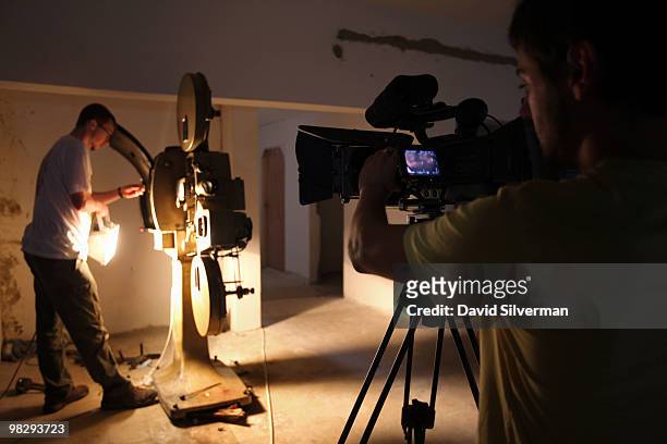 German cameraman Michele Gentile takes footage of a volunteer trying to get the old projector to work for a documentary on the Cinema Jenin project...