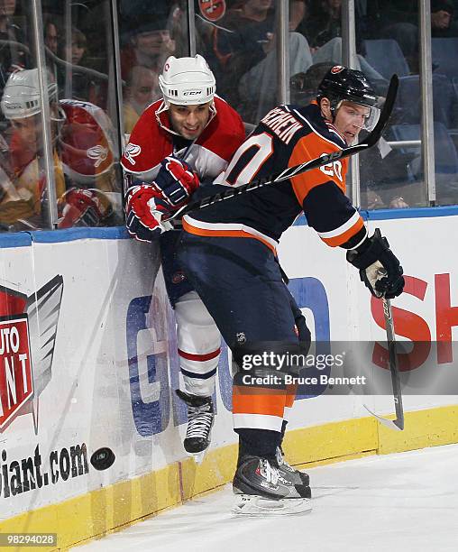 Scott Gomez of the Montreal Canadiens is squeezed into the boards by Sean Bergenheim of the New York Islanders at Nassau Coliseum on April 6, 2010 in...