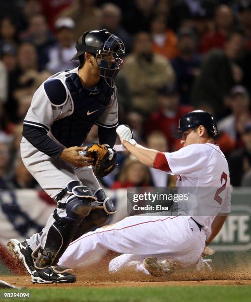 Jacoby Ellsbury of the Boston Red Sox slides home safely past Jorge Posada of the New York Yankees in the first inning on April 6, 2010 at Fenway...