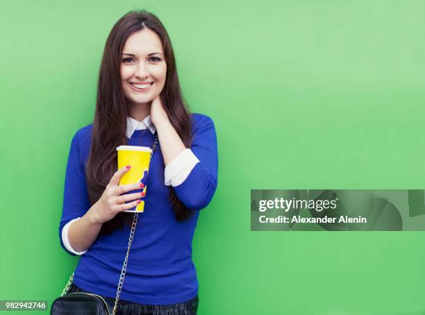 beautiful brunette girl standing with a glass in his hand near the green wall and smiling at the cam - cam girl stock pictures, royalty-free photos & images