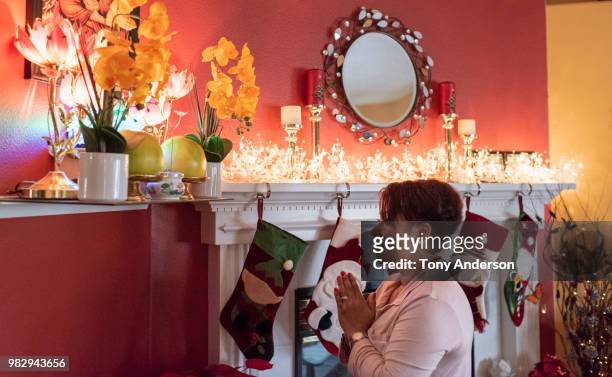 woman praying at buddhist shrine in home decorated for christmas - stocking tops stock pictures, royalty-free photos & images