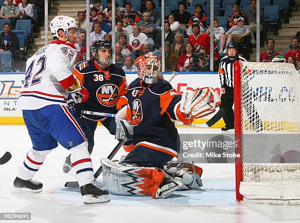 Goaltender Martin Biron of the New York Islanders knocks the puck over the net to make a save as teammate Jack Hillen and Dominic Moore of the...