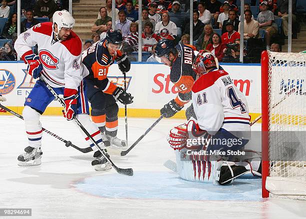 Kyle Okposo and Josh Bailey of the New York Islanders battle for the puck against Roman Hamrlik of the Montreal Canadiens as teammate Jaroslav Halak...