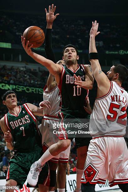Carlos Delfino of the Milwaukee Bucks shoots a layup against Taj Gibson and Brad Miller of the Chicago Bulls on April 6, 2010 at the United Center in...