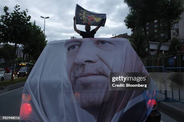 Man holds a flag while traveling in an vehicle adorned with the image of Recep Tayyip Erdogan, Turkey's president, outside of the AKP party...