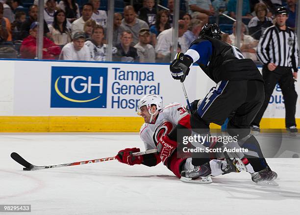 Kurtis Foster of the Tampa Bay Lightning knocks Patrick Dwyer of the Carolina Hurricanes to the ice at the St. Pete Times Forum on April 6, 2010 in...