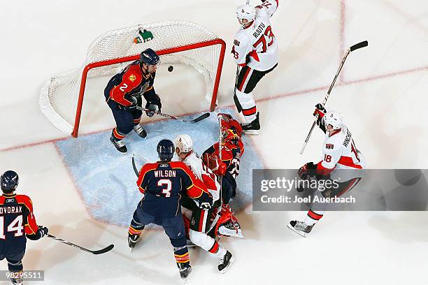 Goaltender Tomas Vokoun of the Florida Panthers looks at the puck after Jarkko Ruutu scored as Jesse Winchester of the Ottawa Senators raises his...