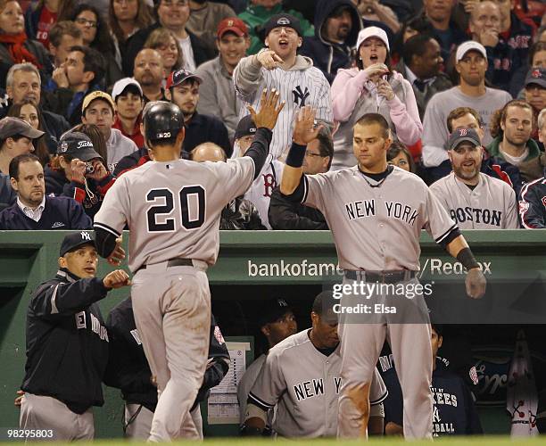 Jorge Posada of the New York Yankees is congratulated by teammates in the dugout after he scored a run on a bases loaded walk in the eighth inning...