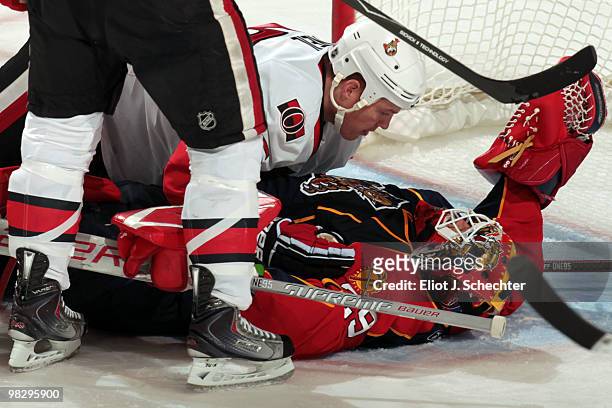Jarkko Ruutu of the Ottawa Senators scores a goal while teammate Chris Neil lies on top of Goaltender Tomas Vokoun of the Florida Panthers at the...