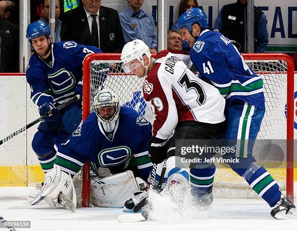 Kevin Bieksa and Roberto Luongo of the Vancouver Canucks look on as their teammate Andrew Alberts battles for the puck against TJ Galiardi of the...