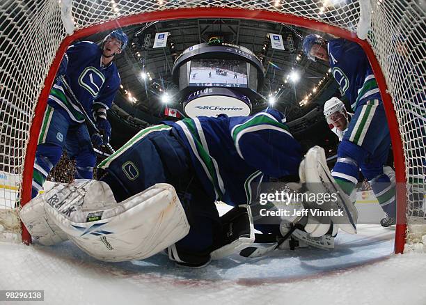 Paul Stastny of the Colorado Avalanche tries to jam the puck past Roberto Luongo of the Vancouver Canucks as Alex Burrows and Henrik Sedin of the...