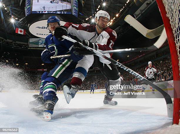 Kyle Quincey of the Colorado Avalanche and Michael Grabner of the Vancouver Canucks battle for the loose puck in front of the net during their game...