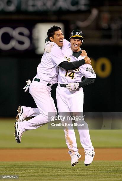 Kurt Suzuki of the Oakland Athletics congratulates Mark Ellis after Ellis got the game-winning hit in the tenth inning against the Seattle Mariners...