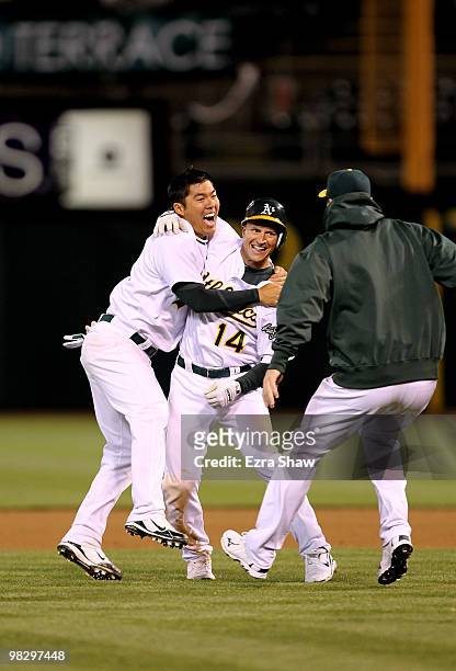 Kurt Suzuki of the Oakland Athletics congratulates Mark Ellis after Ellis got the game-winning hit in the tenth inning against the Seattle Mariners...