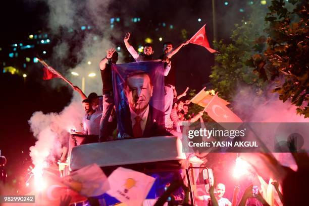 People react and wave flags outside the Justice and Development Party headquarters in Istanbul, on June 24 during the Turkish presidential and...