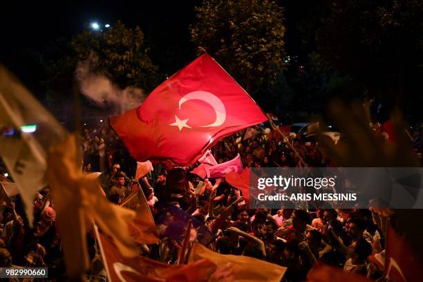 People react and wave flags outside the Justice and Development Party headquarters in Istanbul, on June 24 during the Turkish presidential and...