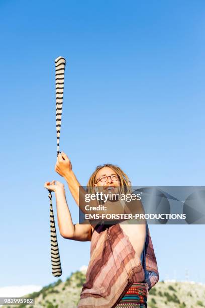 man in his twenties with long blonde dreadlocks poi swinging with striped socks - poi fotografías e imágenes de stock