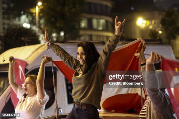 People wave Turkish national flags outside of the AKP party headquarters as they react to the outcome of the parliamentary and presidential elections...