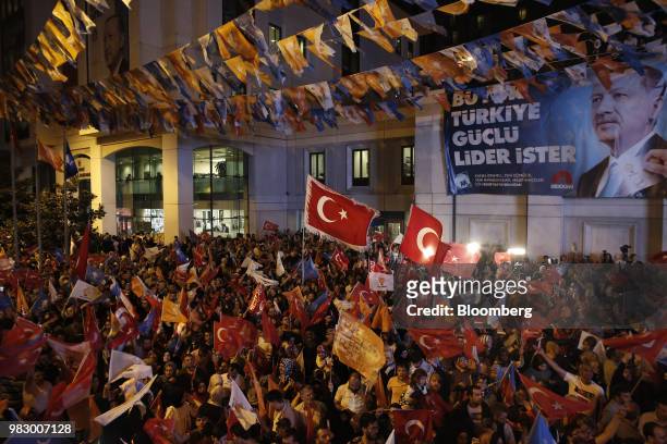 People wave Turkish national flags outside of the AKP party headquarters as they react to the outcome of the parliamentary and presidential elections...