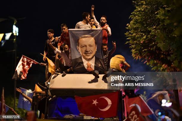 People react and wave flags outside the Justice and Development Party headquarters in Istanbul, on June 24 during the Turkish presidential and...