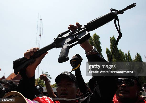 Red shirt supporter of former PM Thaksin Shinawatra shows his weapon after taking the gun from security at Parliament House on April 07, 2010 in...