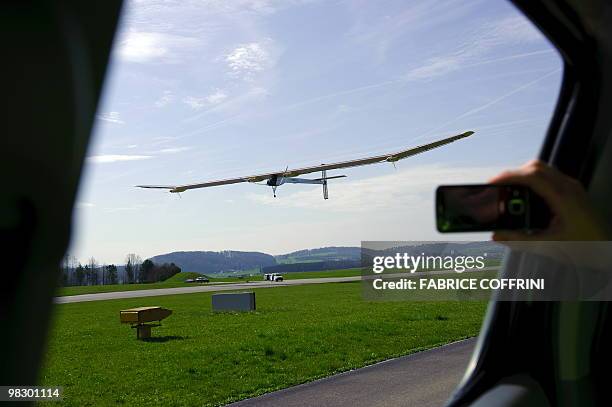 Man snaps a picture with his mobile phone as the Solar Impulse aircraft, a pioneering Swiss bid to fly around the world on solar energy lands after...