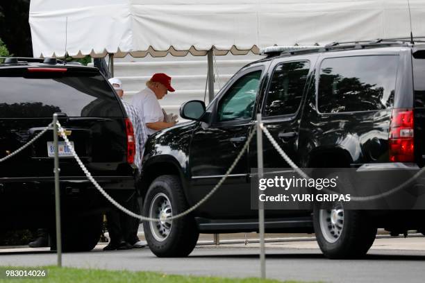 President Donald Trump holds newspapers as he returns to the White House in Washington from Trump National Golf Club in Washington, DC on June 24,...