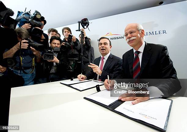 Carlos Ghosn, chief executive officer of Renault SA, left, and Dieter Zetsche, chief executive officer of Daimler AG, sign documents during their...