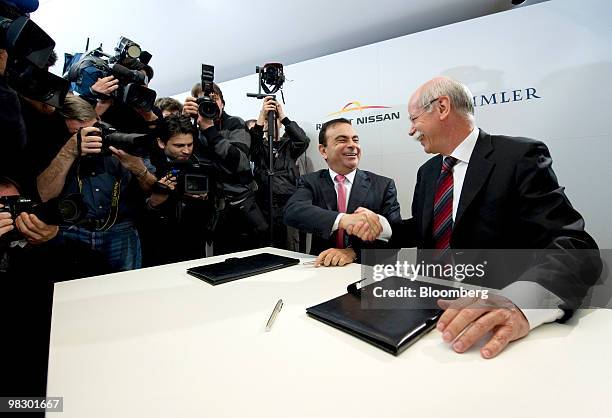 Carlos Ghosn, chief executive officer of Renault SA, left, and Dieter Zetsche, chief executive officer of Daimler AG, shake hands after signing...