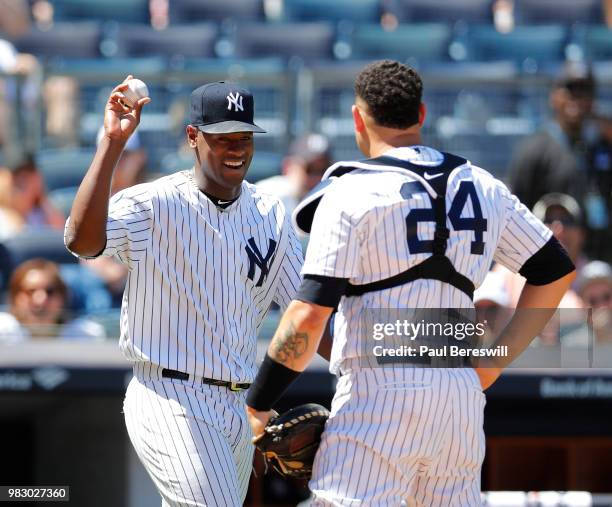 Pitcher Luis Severino of the New York Yankees laughs as he holds the ball up for teammate Gary Sanchez to see after Severino reached in front of...