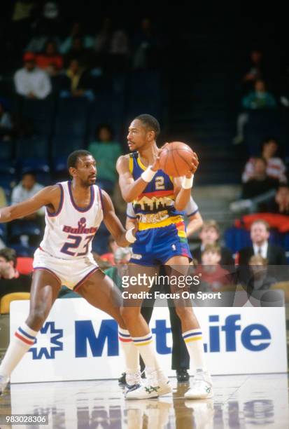 Alex English of the Denver Nuggets looks to pass the ball by Charles Jones of the Washington Bullets during an NBA basketball game circa 1989 at the...