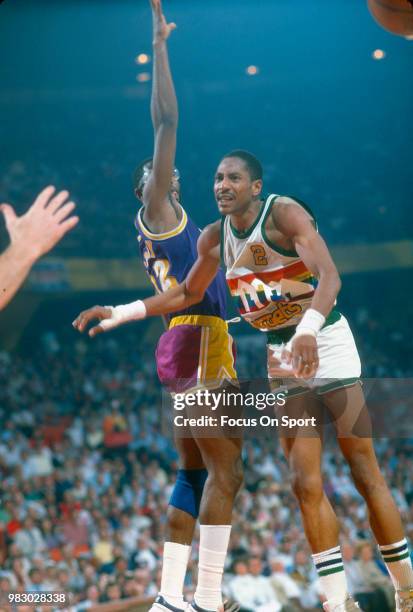 Alex English of the Denver Nuggets passes the ball past James Worthy of the Los Angeles Lakers during an NBA basketball game circa 1985 at McNichols...