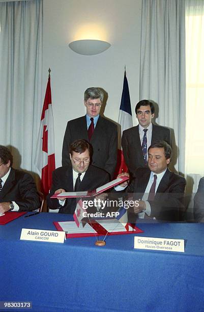 Alain Gourd du CANCOM et Dominique Fagot de Havas Overseas échangent les documents le 23 janvier 1997 à Paris, sous le regard du ministre canadien de...