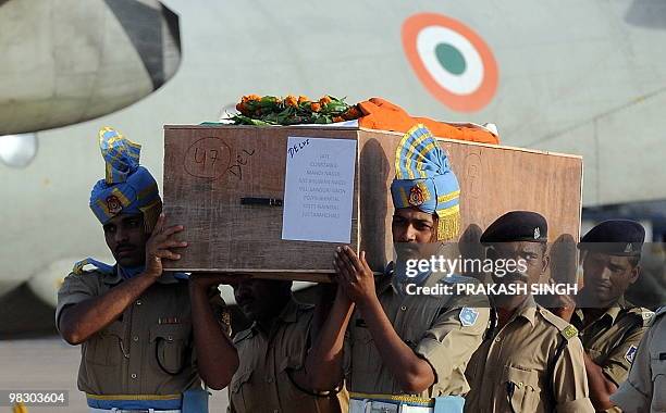 Indian paramilitary officials carry the coffin of a slain Indian Central Reserve Police Force serviceman from an Indian Air Force aircraft at Air...