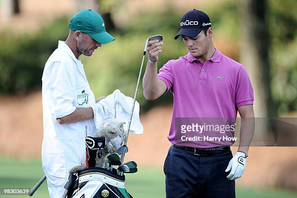 Martin Kaymer of Germany pulls a club from his bag while alongside caddie Justin Grenfell-Hoyle during a practice round prior to the 2010 Masters...