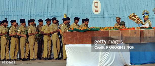 Indian paramilitary Central Reserve Police Force personnel pay tribute in front of the coffins of their fallen comrades during a ceremony at Air...